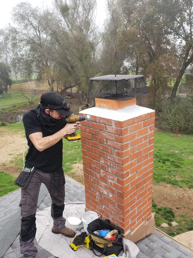Advanced Chimney Sweep Solutions technician sealing a chimney crown and fitting a chimney cap on a Westlake Village rooftop
