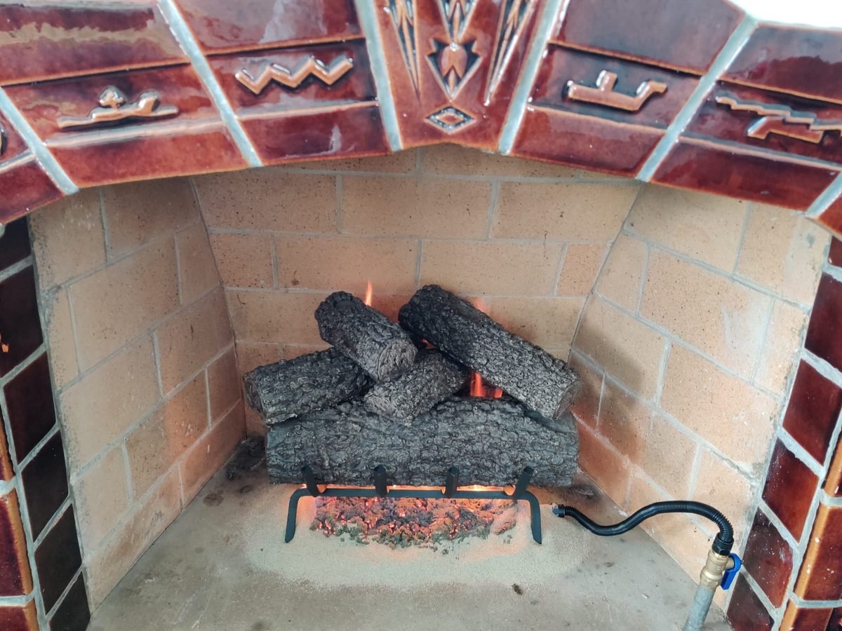 Gas log set correctly positioned over the burner in a decorative tiled firebox after servicing